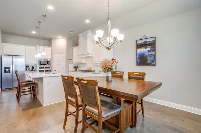 a dining room with wooden floor a chandelier a wooden table and chairs