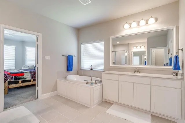 a en suite bathroom with a double vanity sink a mirror and a bathtub