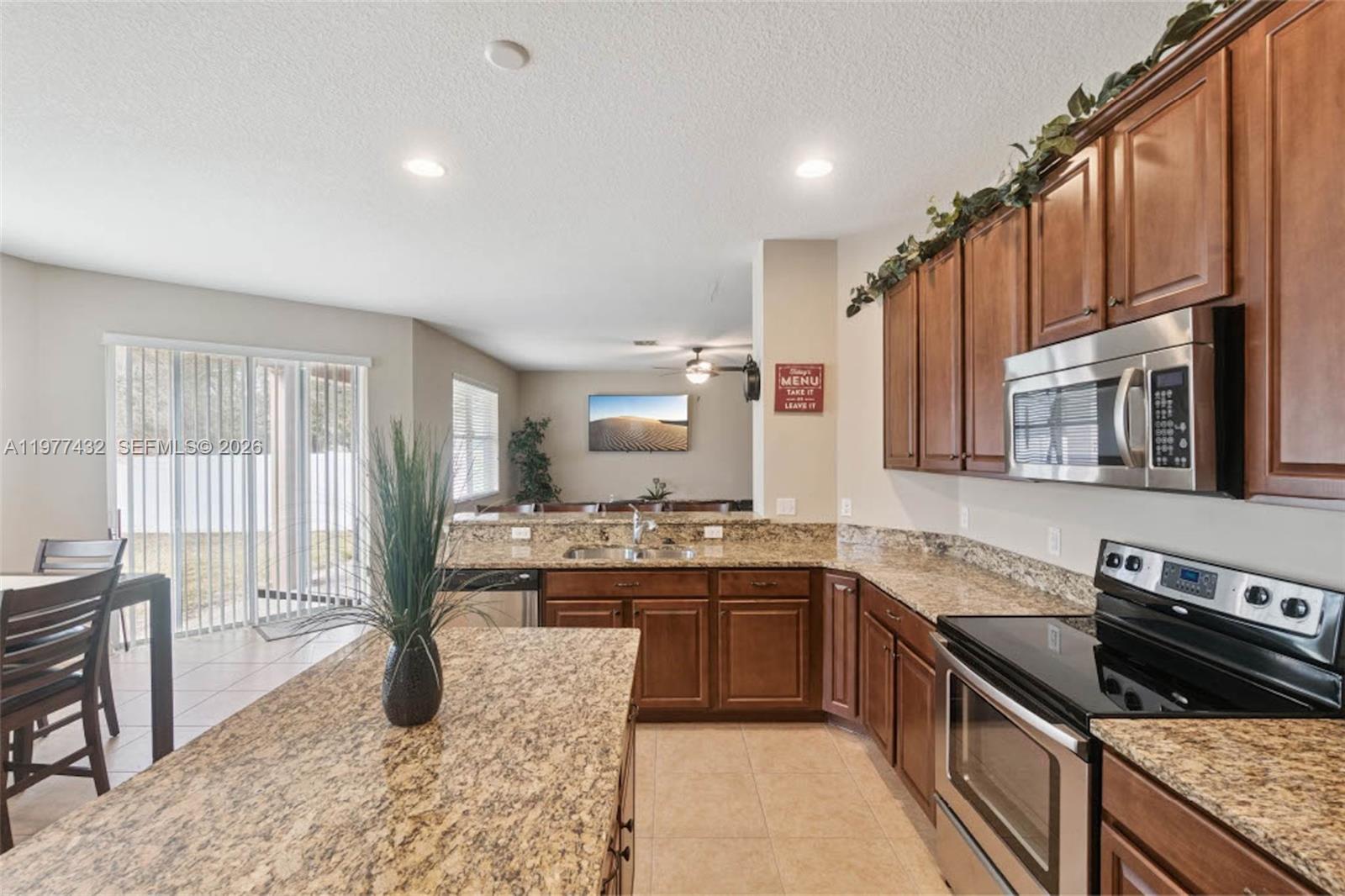 2502 Woodside Ridge Drive Apopka, FL 32712 - Photo 6 of 37 a kitchen with stainless steel appliances granite countertop a stove top oven a sink a dining table and chairs