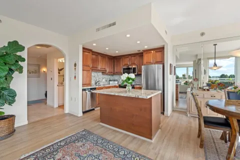 a kitchen with stainless steel appliances granite countertop a refrigerator a stove a sink a dining table and chairs with wooden floor