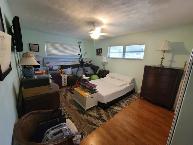a living room with furniture a flat screen tv and a refrigerator
