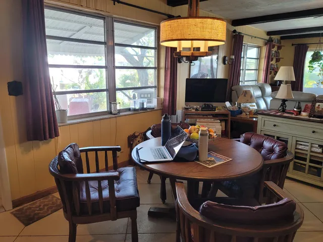 a dining room with furniture wooden floor a rug a potted plant and a chandelier