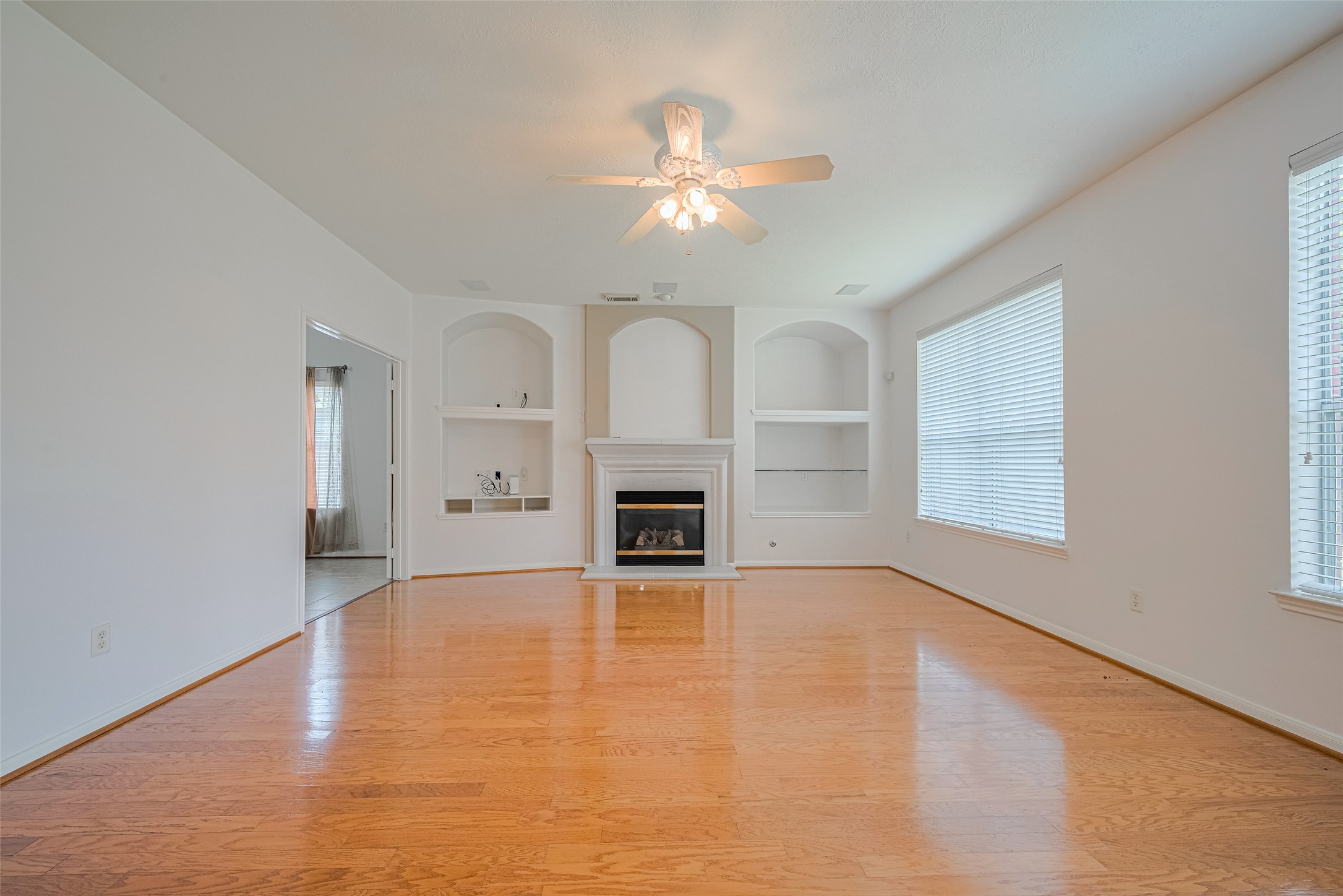 9218 Memorial Pines Way Spring, TX 77379 - Photo 14 of 39 Bright living room with hardwood floors, built-in shelves, and a cozy fireplace enhanced by the natural light from the large windows overlooking the backyard.