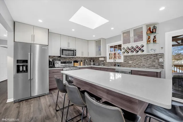 a kitchen with stainless steel appliances granite countertop a refrigerator a stove and a wooden floors