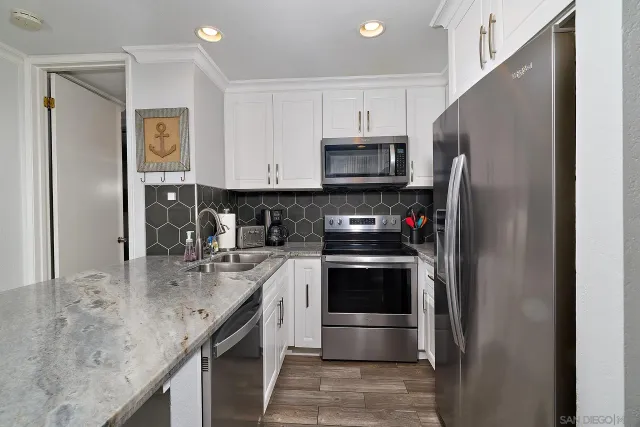 a kitchen with stainless steel appliances granite countertop a refrigerator a stove and a sink