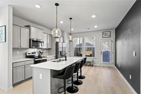 a open kitchen with stainless steel appliances granite countertop a stove top oven a refrigerator a sink dishwasher a dining table and chairs with wooden floor