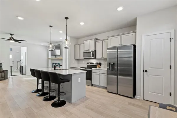 a kitchen with stainless steel appliances a dining table chairs refrigerator and cabinets