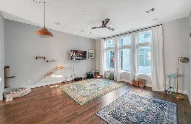 a view of a livingroom with wooden floor and a ceiling fan