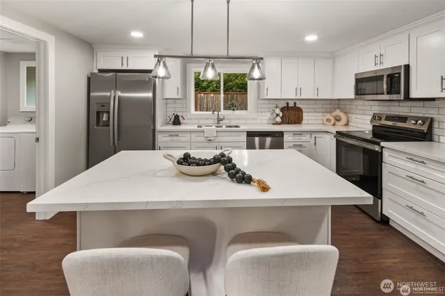 a kitchen with stainless steel appliances a table chairs and a refrigerator
