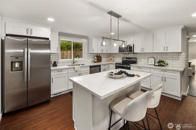 a kitchen with stainless steel appliances a stove a sink a refrigerator a center island and a window