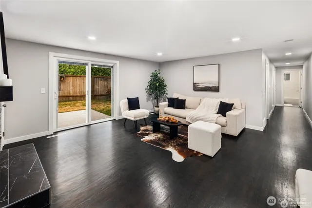 a living room with couches and a potted plant next to a window