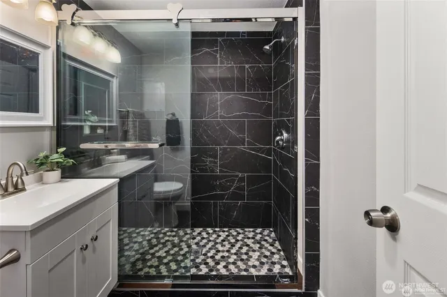 a bathroom with a sink a toilet a mirror and shower