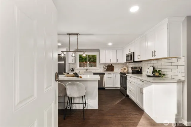 a kitchen with kitchen island a stove a sink a refrigerator wooden floor cabinets and dining table