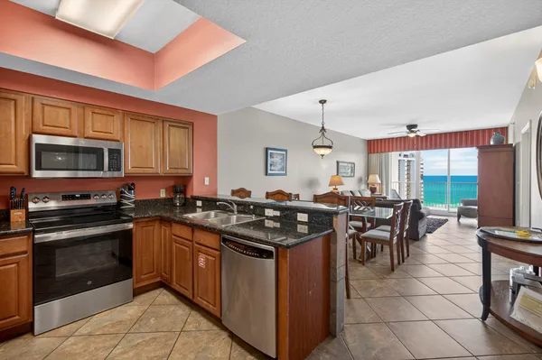 a kitchen with stainless steel appliances granite countertop a stove top oven a sink dishwasher a dining table and chairs with wooden floor