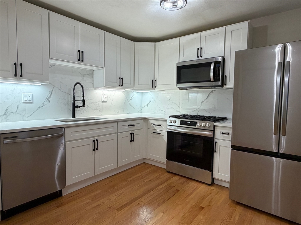 4 Chesterton Street, Unit 2 Boston, MA 02119 - Photo 1 of 9 a kitchen with cabinets stainless steel appliances and wooden floor