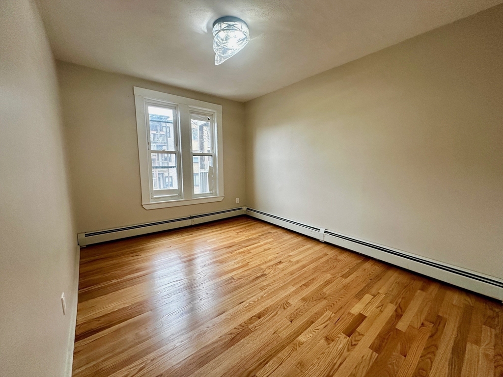 4 Chesterton Street, Unit 2 Boston, MA 02119 - Photo 5 of 9 an empty room with wooden floor and windows