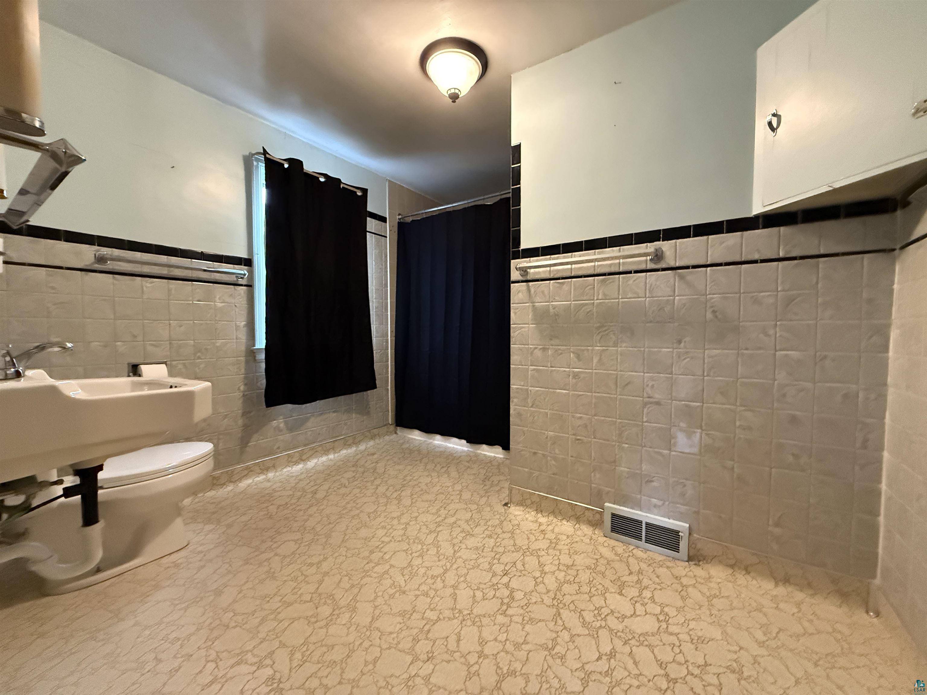 3001 3rd Avenue West Hibbing, MN 55746 - Photo 21 of 38 Full bathroom featuring tile walls, wainscoting, and a stall shower
