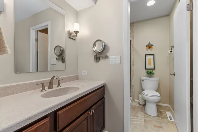 a bathroom with a granite countertop sink a toilet and a mirror