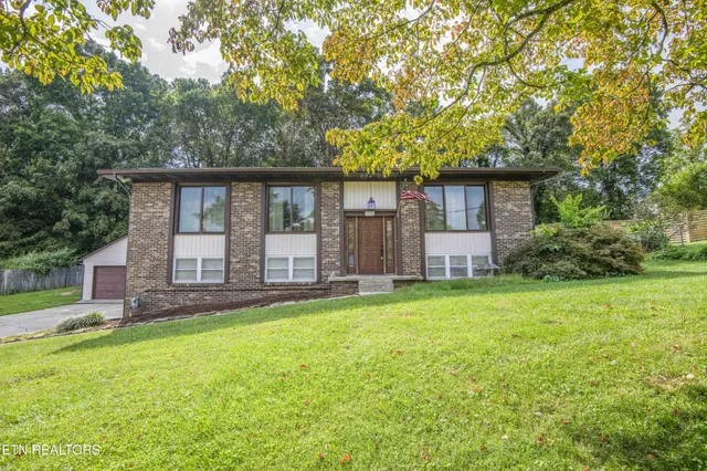 a view of a house with backyard and a tree