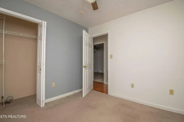 an empty room with closet and a ceiling fan