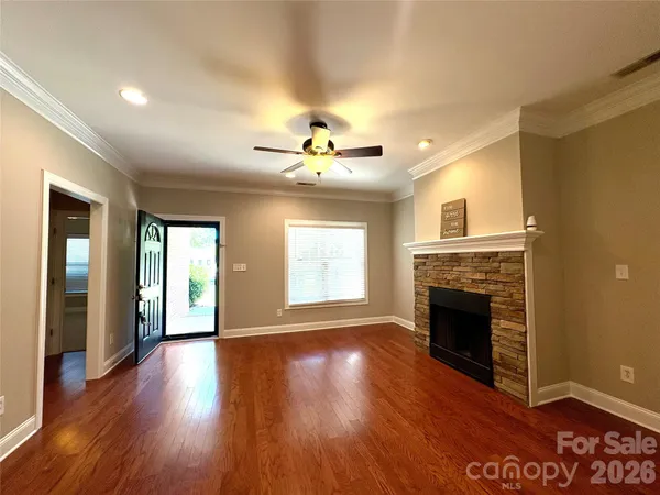 a view of an empty room with wooden floor and a fireplace