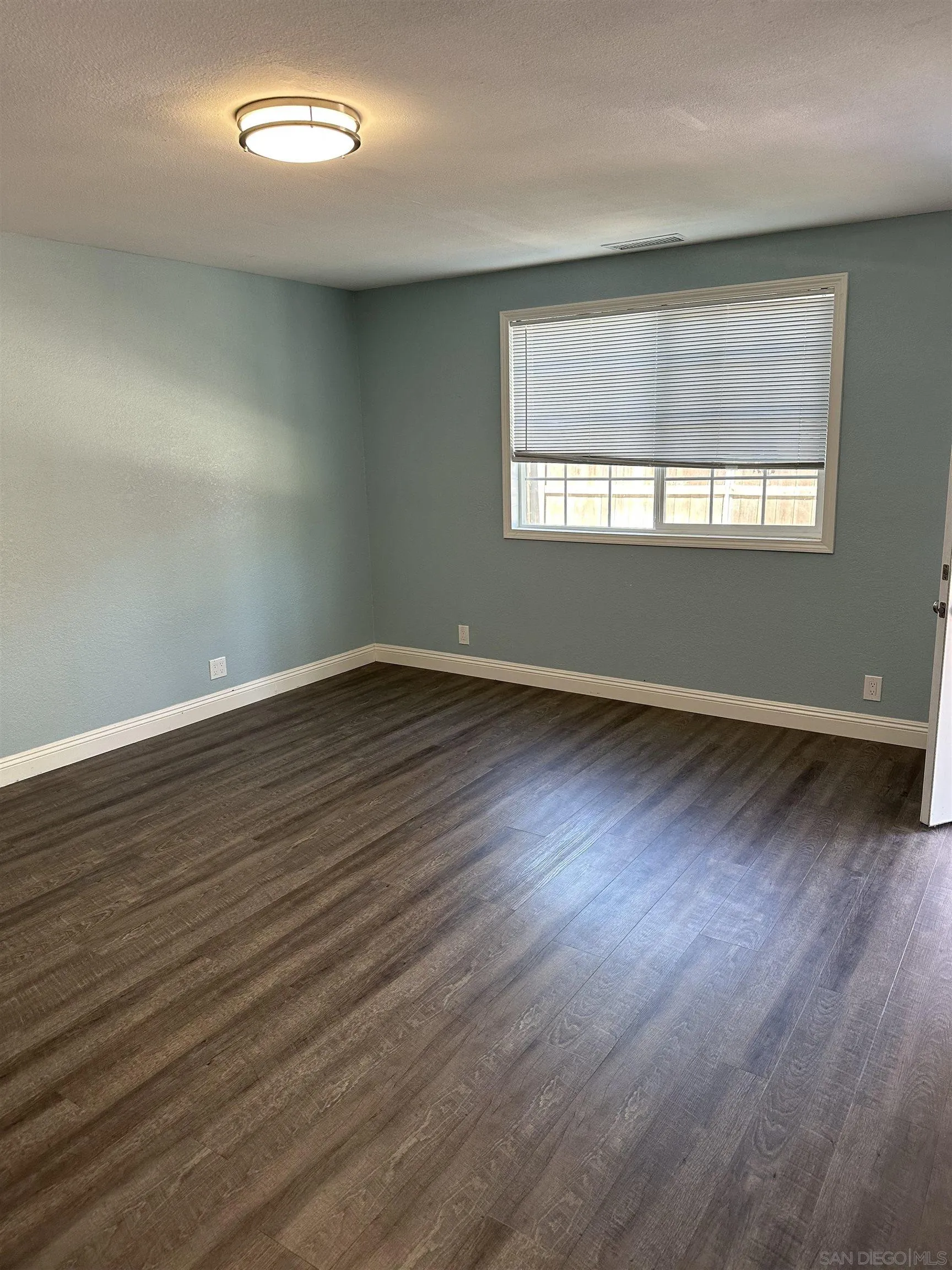 10762 Fenwick Road San Diego, CA 92126 - Photo 4 of 10 an empty room with wooden floor and windows