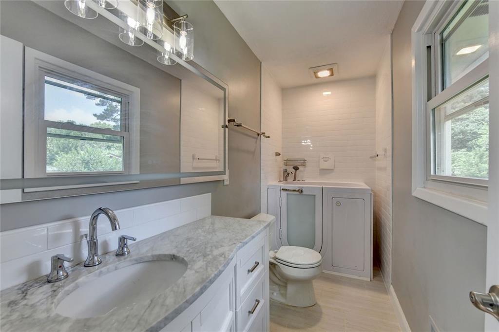 1577 Harbour Oaks Road Tucker, GA 30084 - Photo 31 of 58 a bathroom with a granite countertop toilet a sink and a large mirror