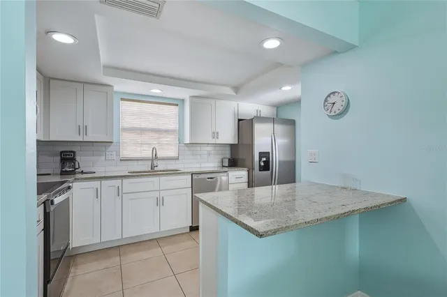 a kitchen with granite countertop stainless steel appliances a sink a stove a counter top space and cabinets