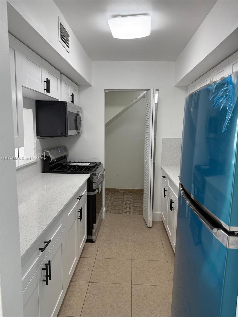 1255 West 53rd Street, Unit 202 Hialeah, FL 33012 - Photo 3 of 11 a kitchen with a refrigerator and a stove top oven