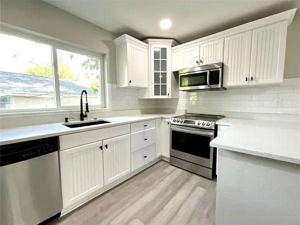 a kitchen with kitchen island white cabinets and appliances