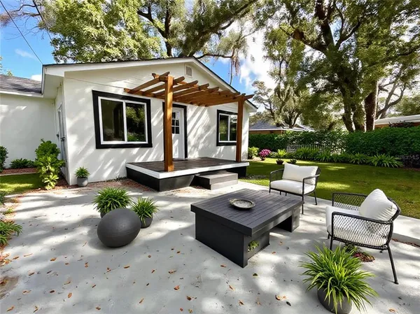 a view of a patio with couches table and chairs with potted plants and large tree