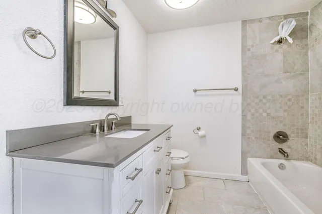 a bathroom with a granite countertop sink a toilet and a bathtub