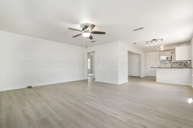 an empty room with a kitchen and a ceiling fan