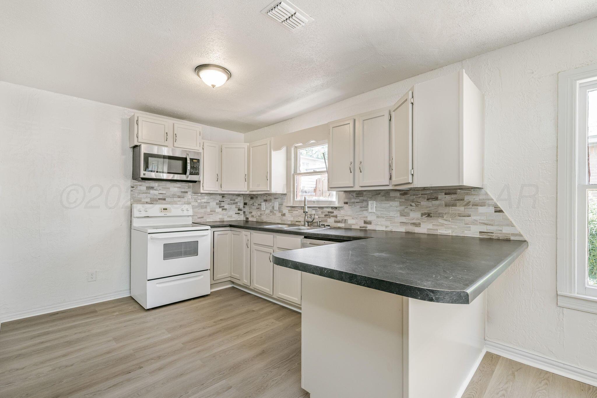 606 Sunset Terrace Amarillo, TX 79106 - Photo 5 of 16 a kitchen with granite countertop white cabinets and white appliances