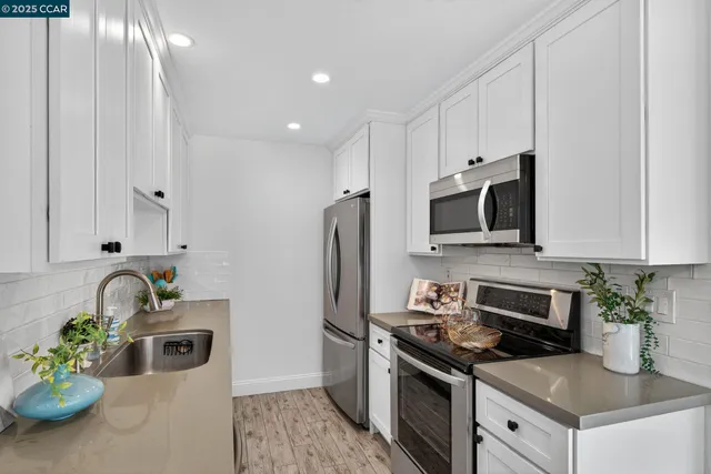 a kitchen with stainless steel appliances a stove a sink a microwave a refrigerator and cabinets