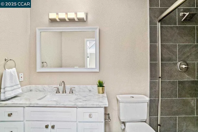 a bathroom with a granite countertop sink vanity mirror and toilet