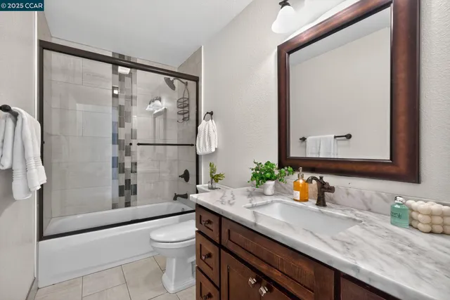 a bathroom with a granite countertop sink toilet a mirror and shower