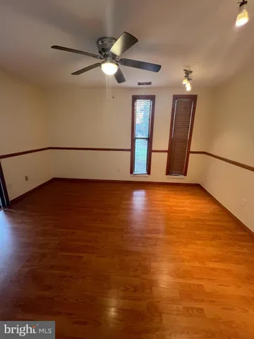 a view of an empty room with window and wooden floor