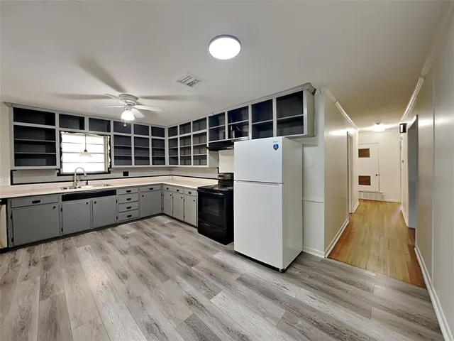 a large kitchen with a large counter top space a sink stainless steel appliances and cabinets