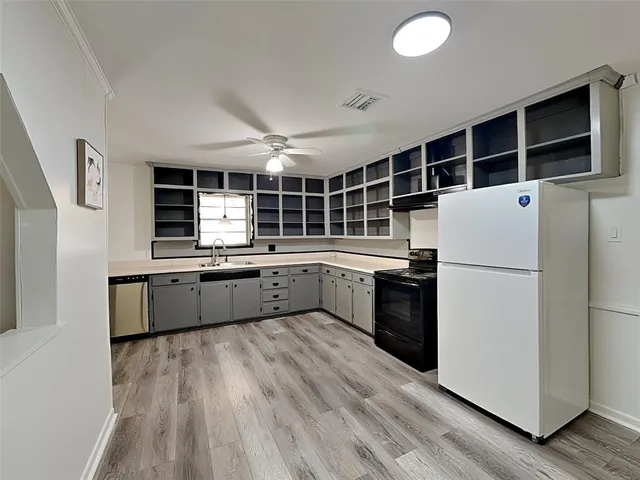 a kitchen with stainless steel appliances a refrigerator a sink a stove with wooden floor