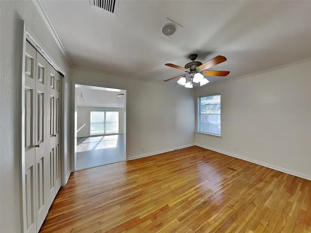 a view of an empty room with a window and wooden floor