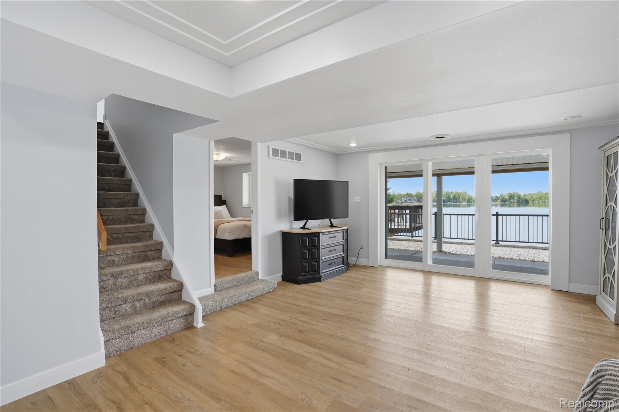 7217 Andersonville Road Clarkston, MI 48346 - Photo 36 of 65 Expansive room featuring wood-finish flooring, a coffered ceiling, and a full wall of glass doors opening to a waterfront balcony