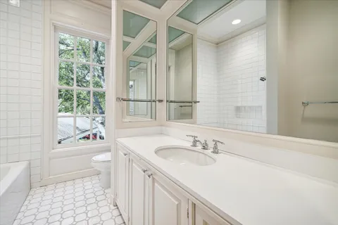 a bathroom with a granite countertop sink a toilet a mirror shower and bathtub
