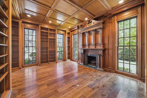 an empty room with wooden floor fireplace and windows
