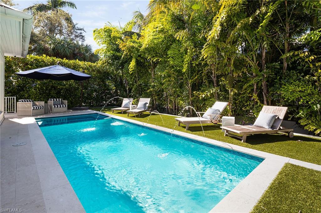 1040 2nd Street South Naples, FL 34102 - Photo 32 of 42 a view of a swimming pool with a table and chairs under an umbrella