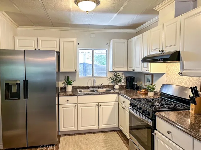 a kitchen with stainless steel appliances granite countertop a stove a refrigerator and a sink