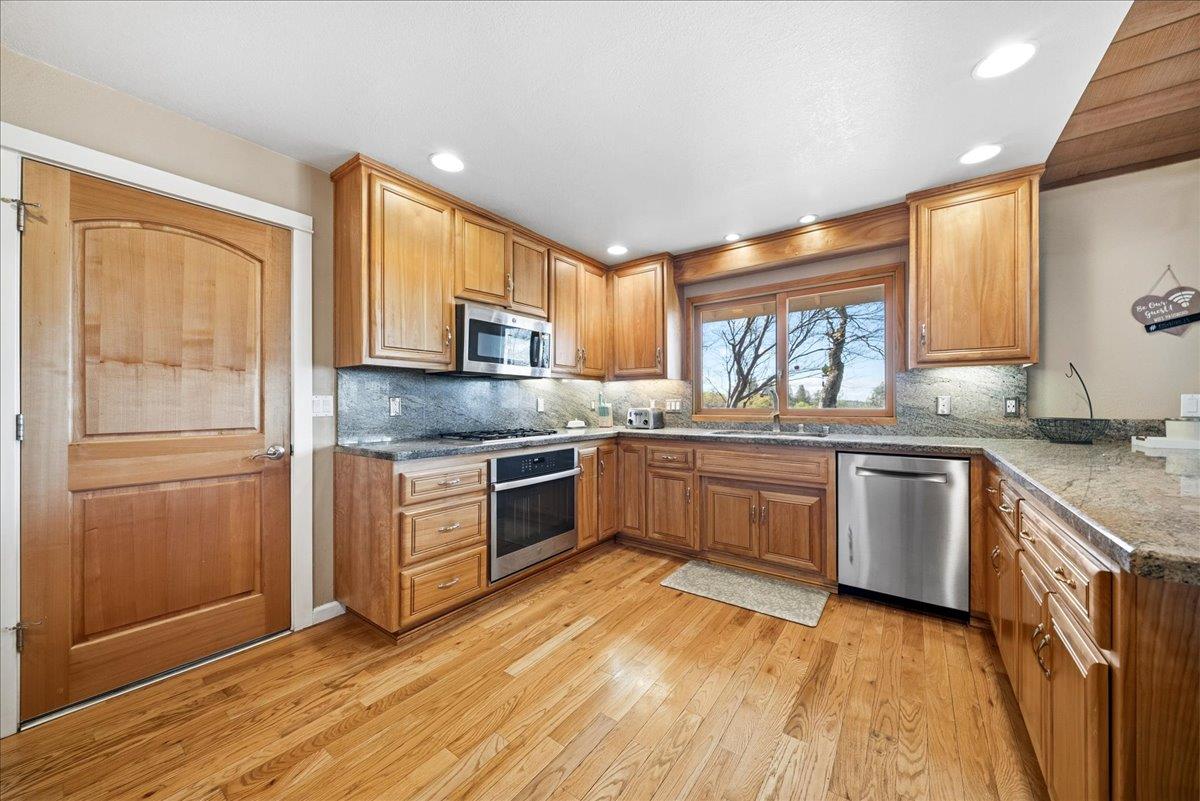 16035 Running Springs Road Grass Valley, CA 95949 - Photo 11 of 94 a kitchen with granite countertop wooden floors stainless steel appliances a sink and a window