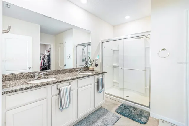 a bathroom with a granite countertop sink a mirror and a shower