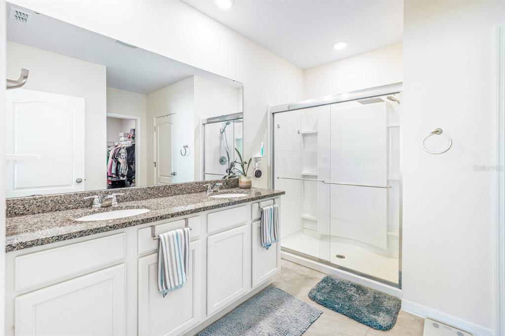 5381 Hickory Downs Way St. Cloud, FL 34771 - Photo 19 of 35 a bathroom with a granite countertop sink a mirror and a shower
