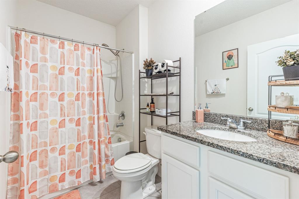 5381 Hickory Downs Way St. Cloud, FL 34771 - Photo 22 of 35 a bathroom with a granite countertop sink a toilet and a mirror